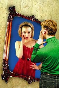 Boy reflecting as  girl in the mirror. 